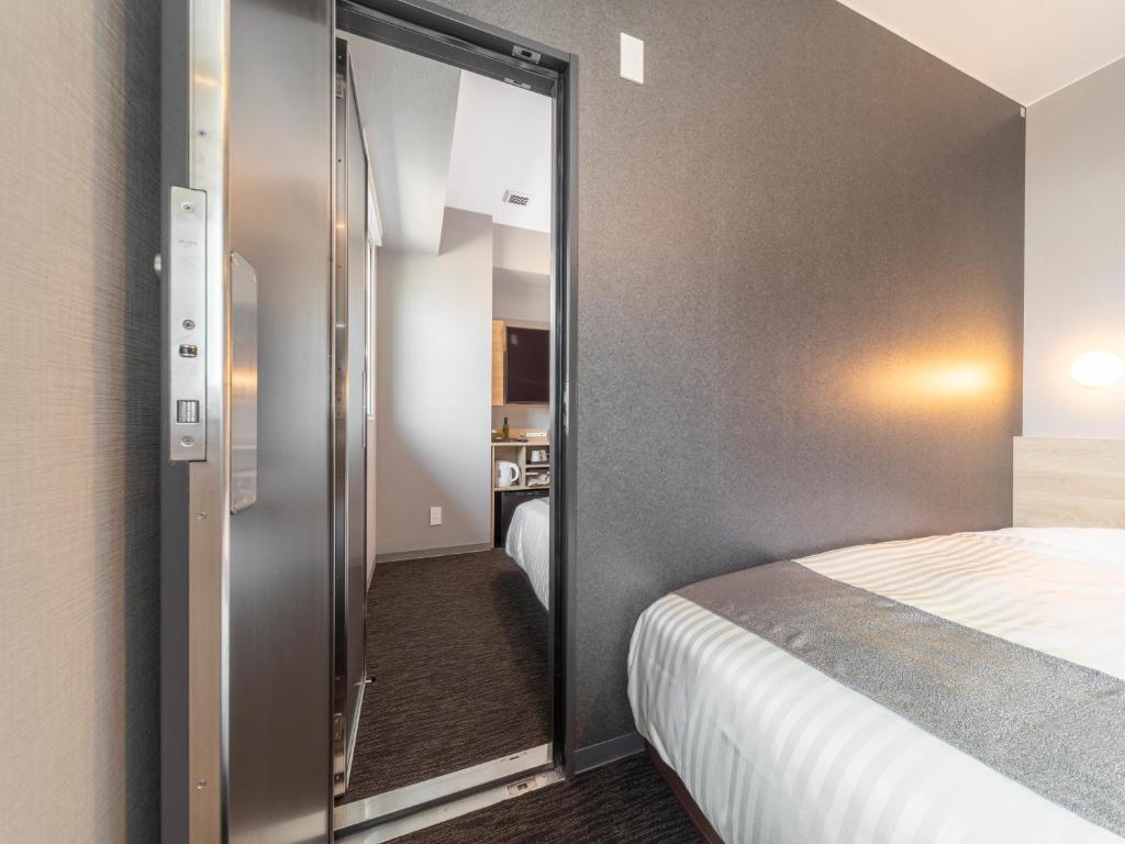 a room with a bed and a sliding glass door at Super Hotel Premier Kanazawaeki Higashiguchi in Kanazawa