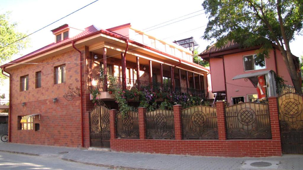 a red brick building with a balcony with plants on it at Pensiunea Pluto Sulina in Sulina