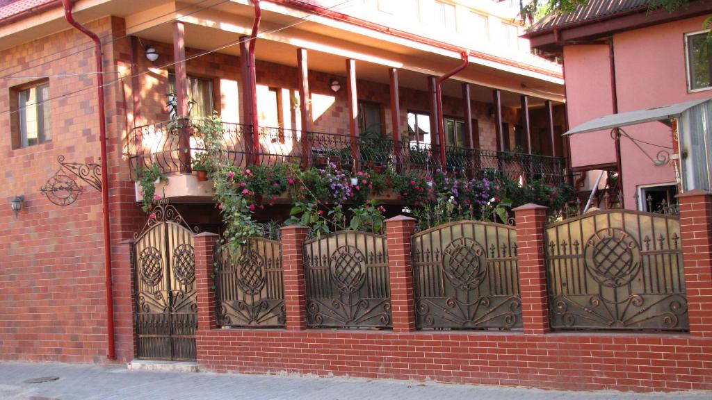 a brick building with a fence with flowers on it at Pensiunea Pluto Sulina in Sulina