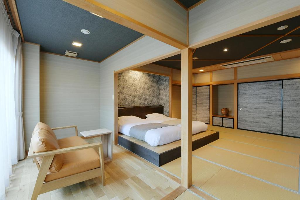1 dormitorio con 1 cama y 1 silla en Hanasuishou en Fuefuki