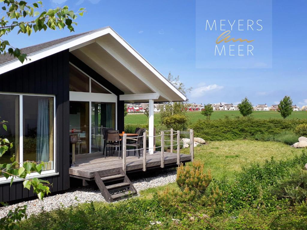 a small house with a porch and a deck at Schwarzes Holzferienhaus mit Sauna -- L I E B L I N G S P L A T Z -- an der Ostsee, Zierow bei Wismar, Strand 500m, alles inklusive in Zierow