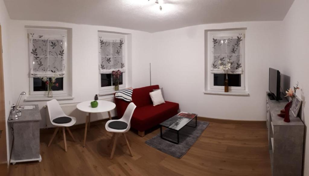Habrachćicy的住宿－gemütliche Ferienwohnung in der Oberlausitz，客厅配有红色的沙发和桌子
