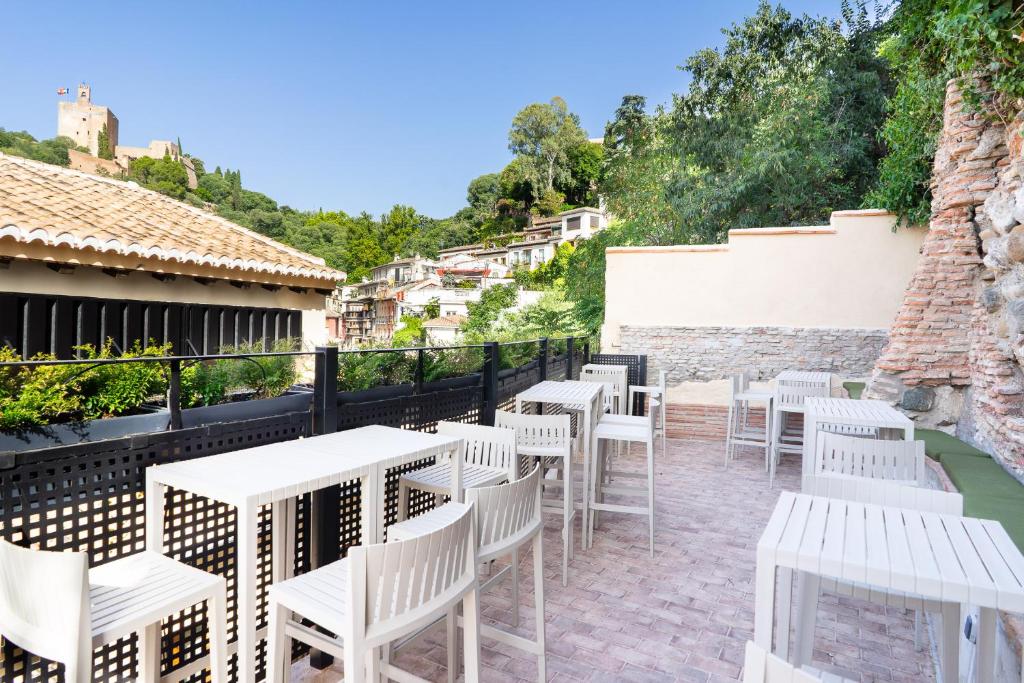 una fila de mesas y sillas blancas en un patio en Hotel Boutique Puerta de las Granadas en Granada