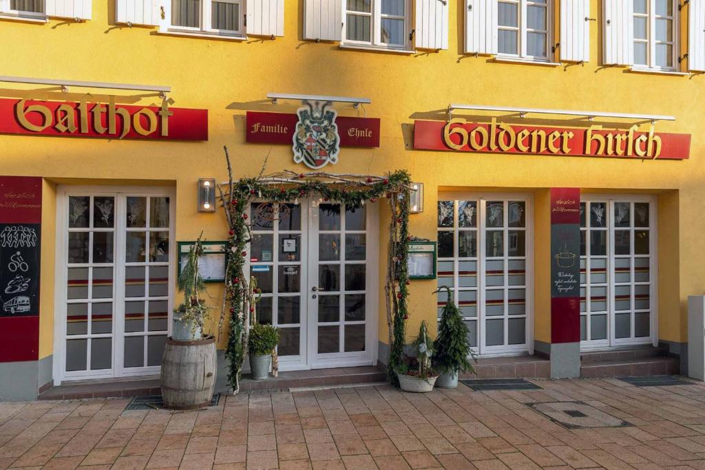 un edificio amarillo con puertas y letreros. en Hotel Restaurant Goldener Hirsch, en Donauwörth