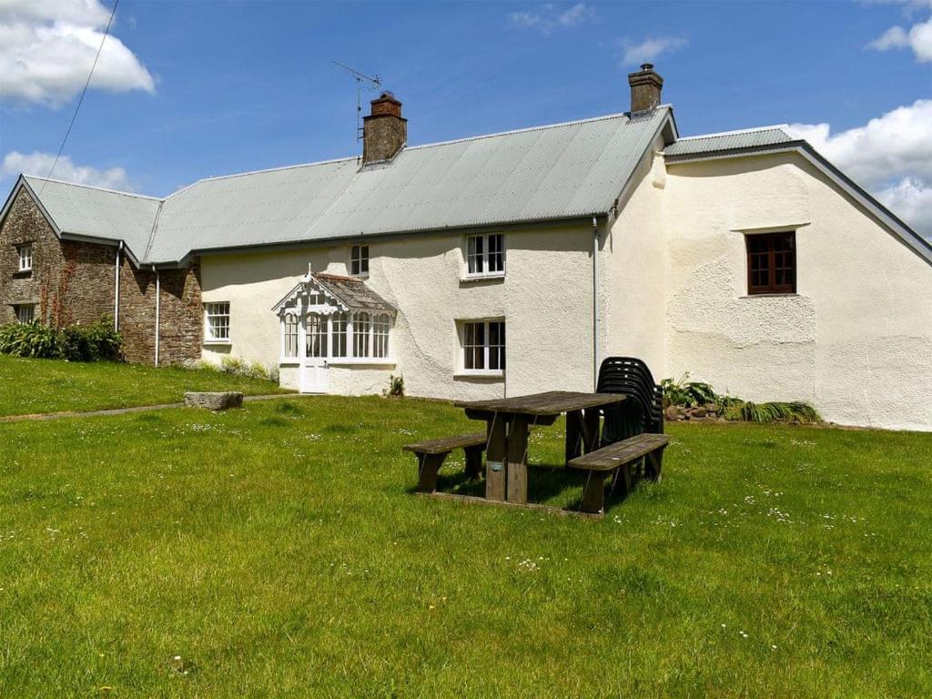 a picnic table in front of a white house at Well Farm Cottages in North Tamerton
