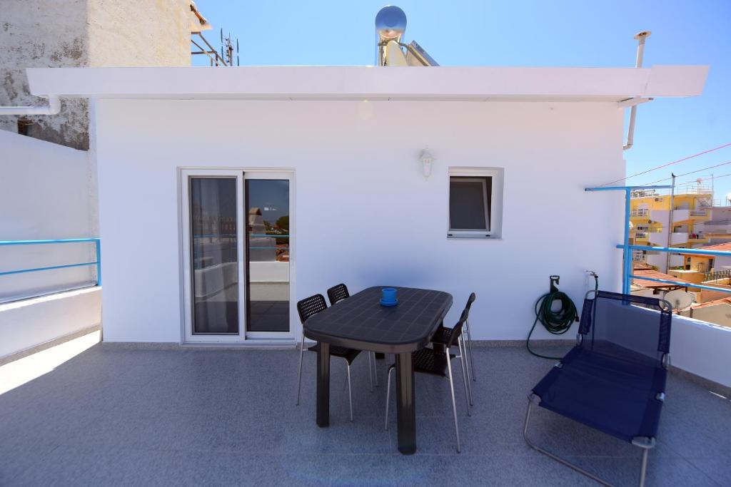 una mesa y sillas sentadas en un balcón en Happy Days Home Apartment und Studio/Penthouse en Ialyssos
