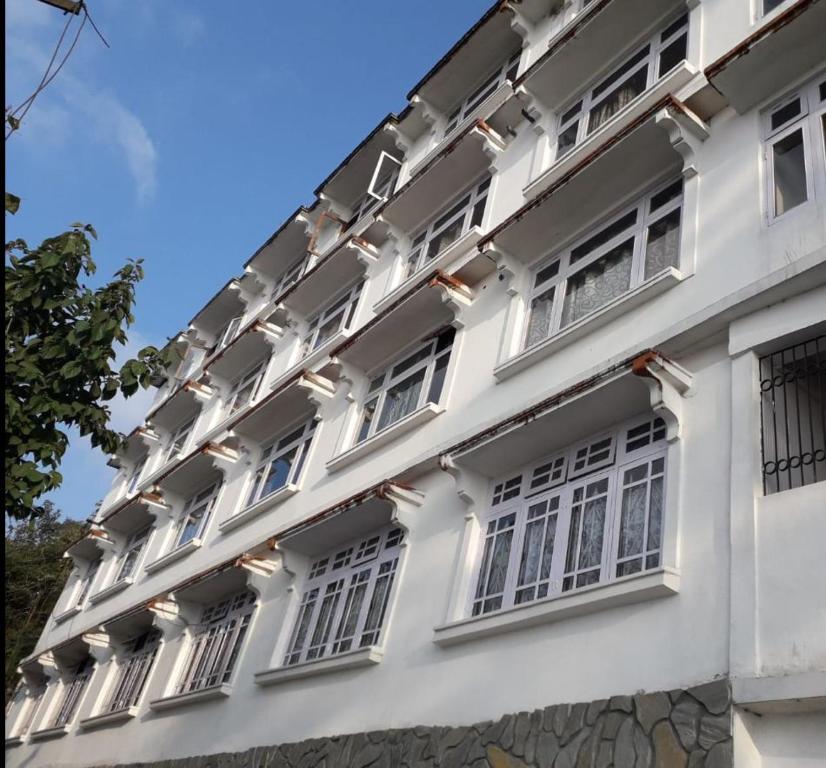 - un bâtiment blanc avec des fenêtres sur le côté dans l'établissement Hotel Taktsang Darjeeling, à Darjeeling