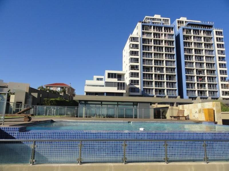 a large swimming pool in front of two tall buildings at Infinity Self Catering Beachfront Apartment 302 in Cape Town