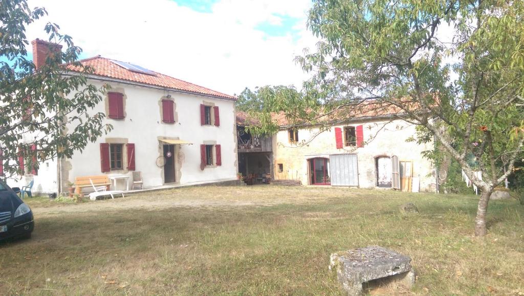 una gran casa blanca con persianas rojas en un patio en Clèdes, en Clèdes