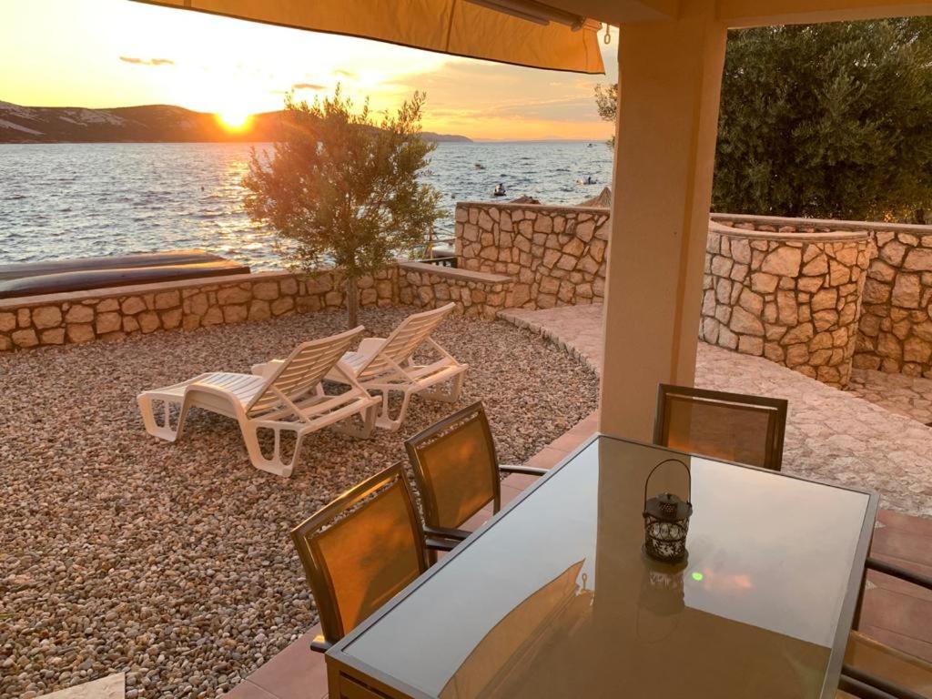 a table and chairs on a patio with a view of the water at Apartments Andrea in Stara Novalja