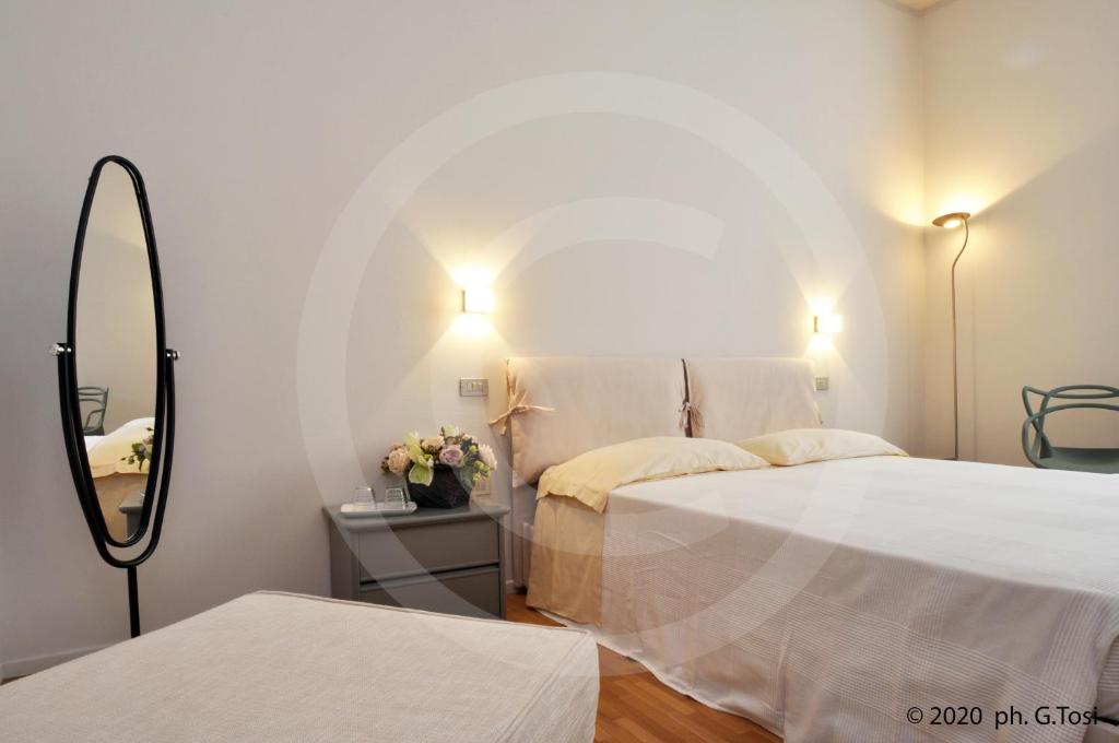 a white bedroom with two beds and a mirror at A.A.A. Armonie B&B in Mantova
