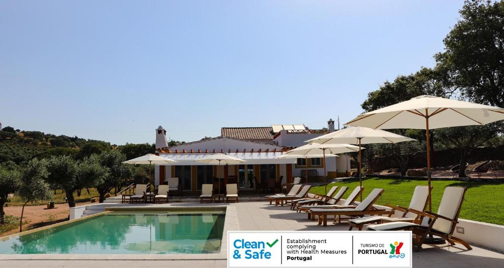 a resort with a swimming pool with chairs and umbrellas at Quinta da Soneca in Alandroal