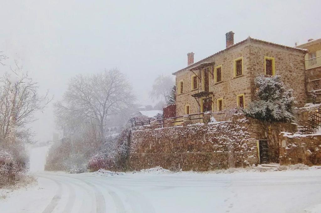 a house in the snow in front of a street at Vitsi Lodge in Sidhirokhórion
