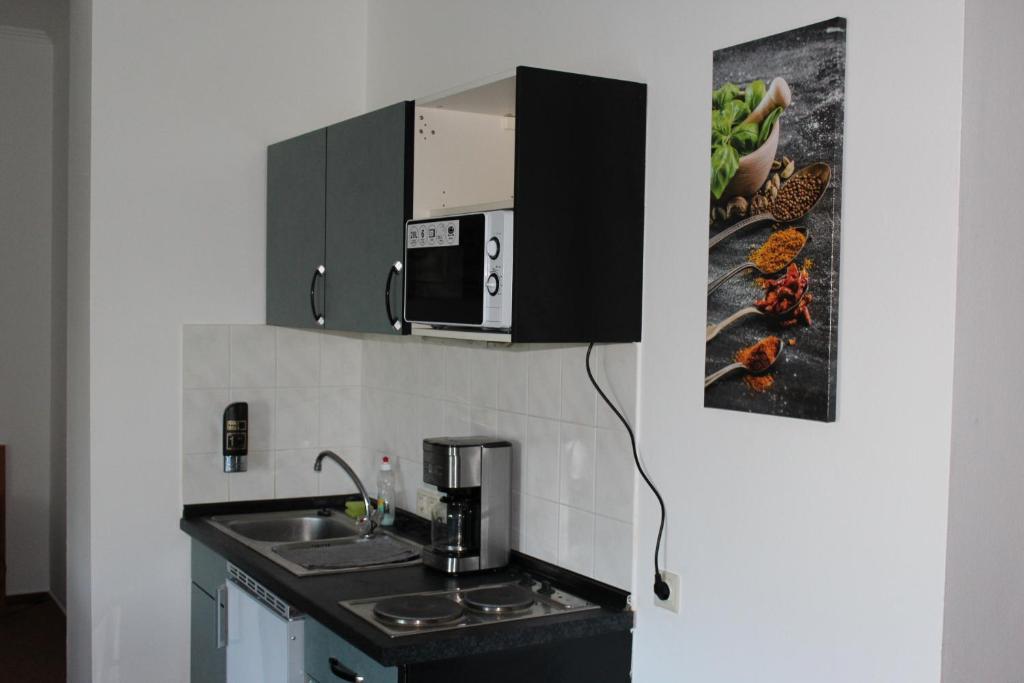eine Küche mit einer Spüle und einer Mikrowelle in der Unterkunft Apartment Hotel in Henstedt-Ulzburg