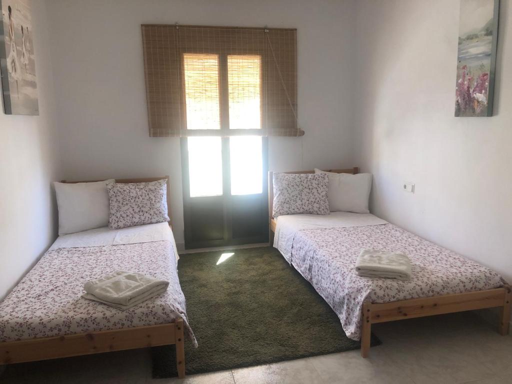 a room with two beds and a window at Casa Sinclair in El Colmenar