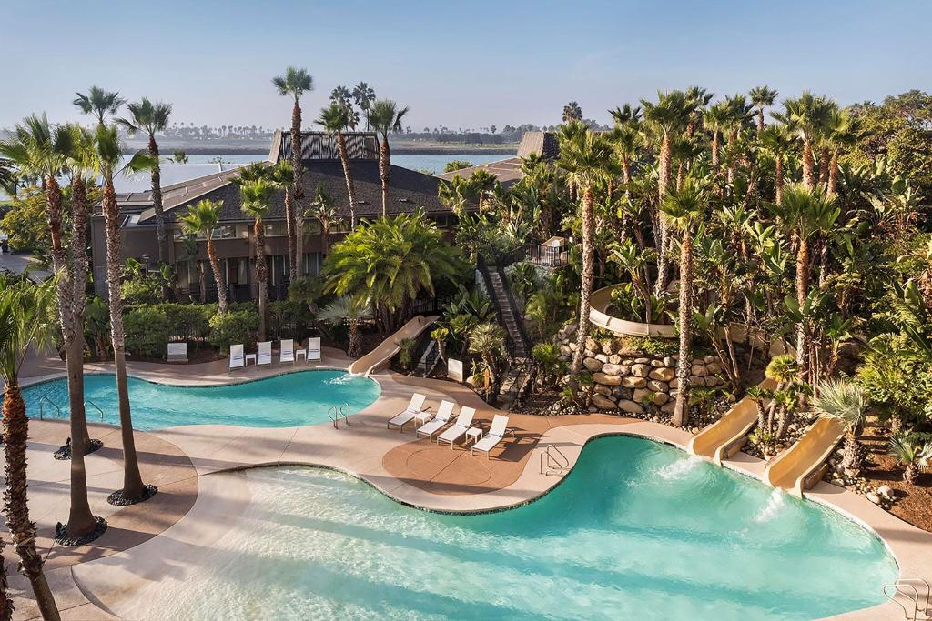 
a beach scene with a pool, beach chairs, and palm trees at Hyatt Regency Mission Bay Spa and Marina in San Diego
