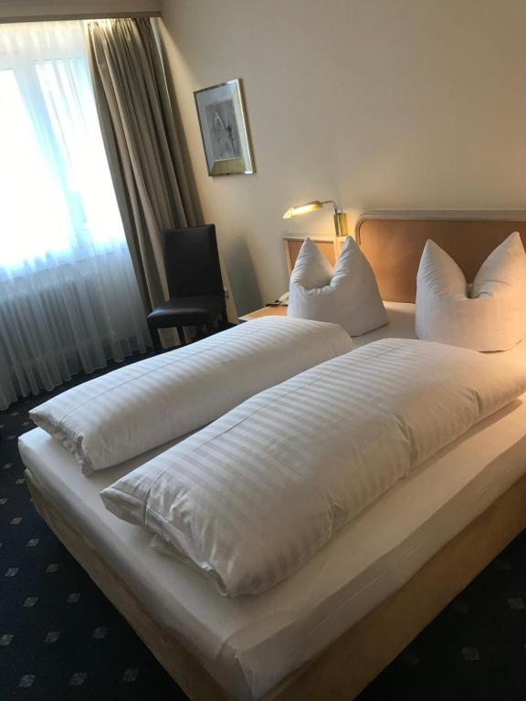 duże białe łóżko w pokoju hotelowym z oknem w obiekcie Hotel Ambiente Garni w Monachium