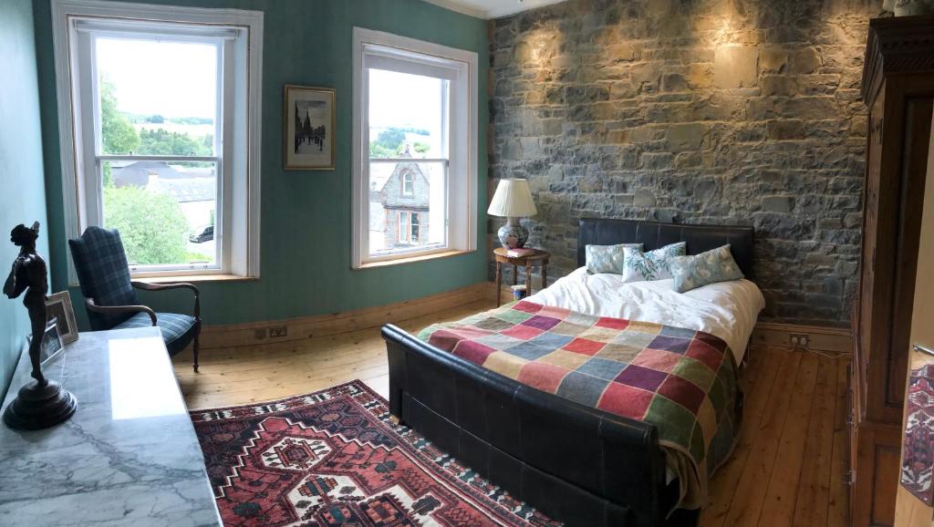 a bedroom with a bed and a brick wall at Kirkview House in Moffat