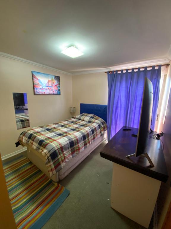 1 dormitorio con 1 cama y escritorio con TV en Habitaciones con baño compartido, en Calama