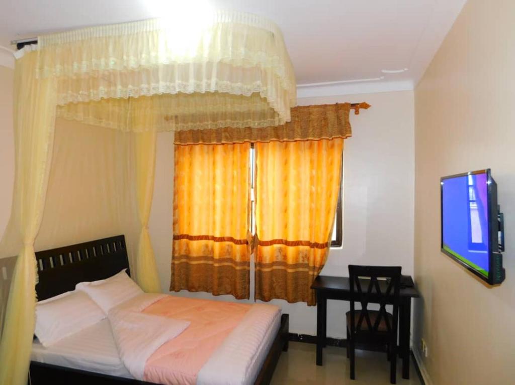 a bedroom with a bed and a window with a television at Range Lands Hotel in Moroto