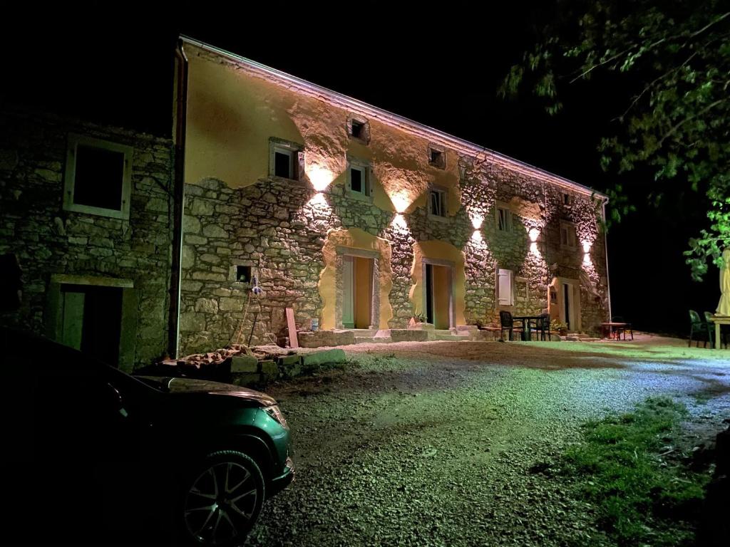 um edifício de pedra com luzes acesas à noite em Skalameri em Kozljak