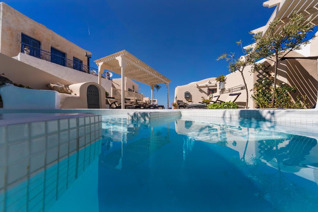 a swimming pool in front of a house with blue water at Lotza Studios in Oia