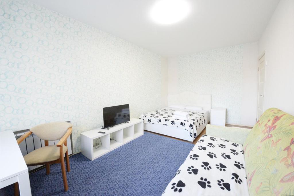モスクワにあるPresnensky Val Apartmentのベッド2台、テレビ、椅子が備わる客室です。