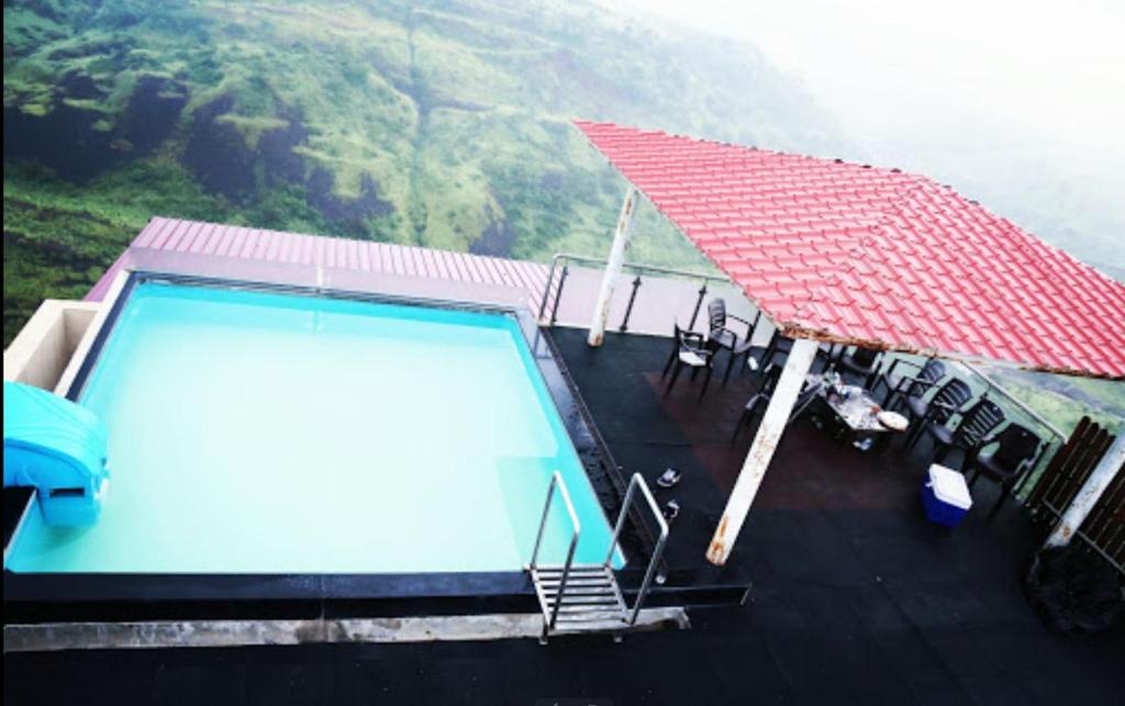 a swimming pool on top of a house with a mountain at Valley View Igatpuri in Igatpuri