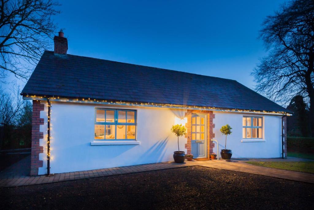 una casa blanca con luces delante en Duneden Cottage and Grounds en Randalstown