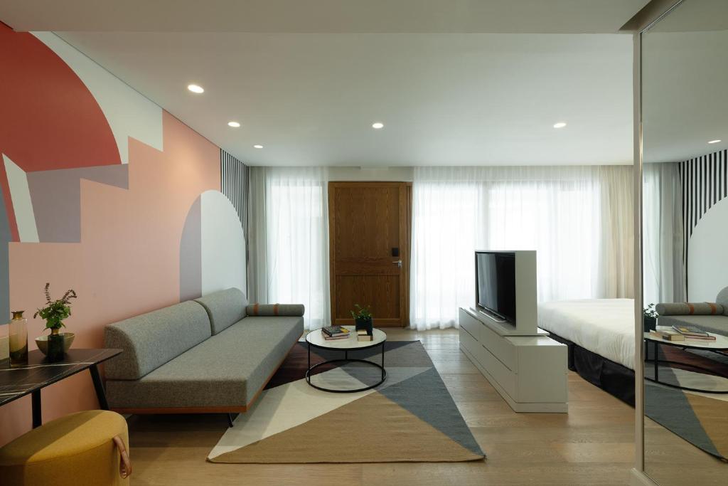 a living room with a couch and a bed and a television at Elma Hotel and Art Complex in Zikhron Ya'akov