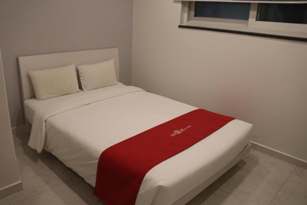 a bed with a red and white blanket on it at Hotel Unique by Foret in Seoul