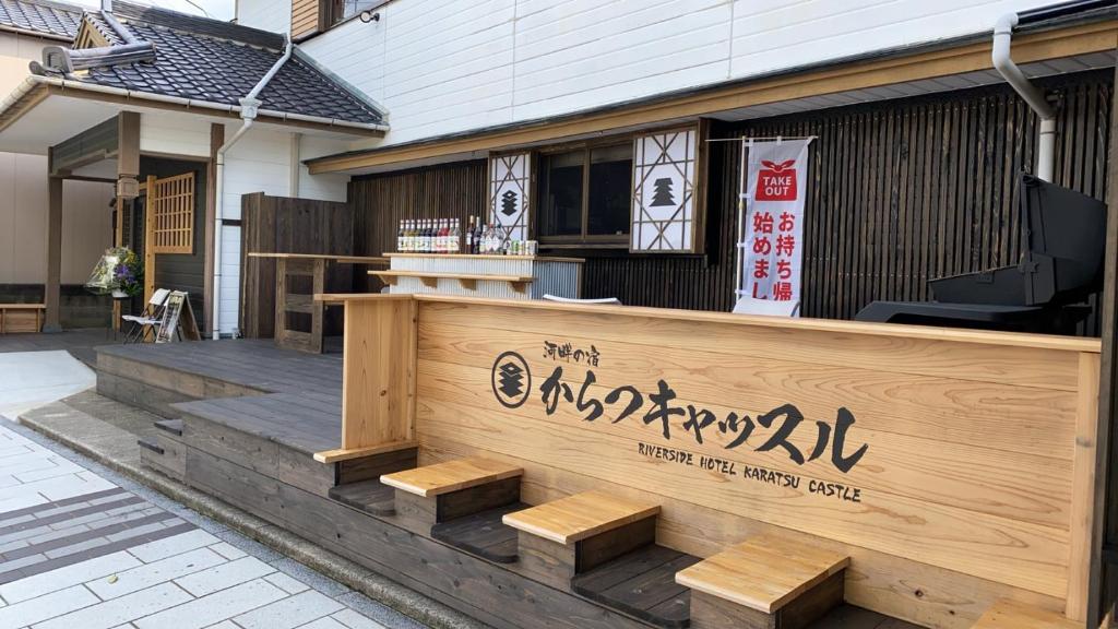 a restaurant with a wooden fence and benches in front of a building at Riverside Hotel Karatsu Castle in Karatsu