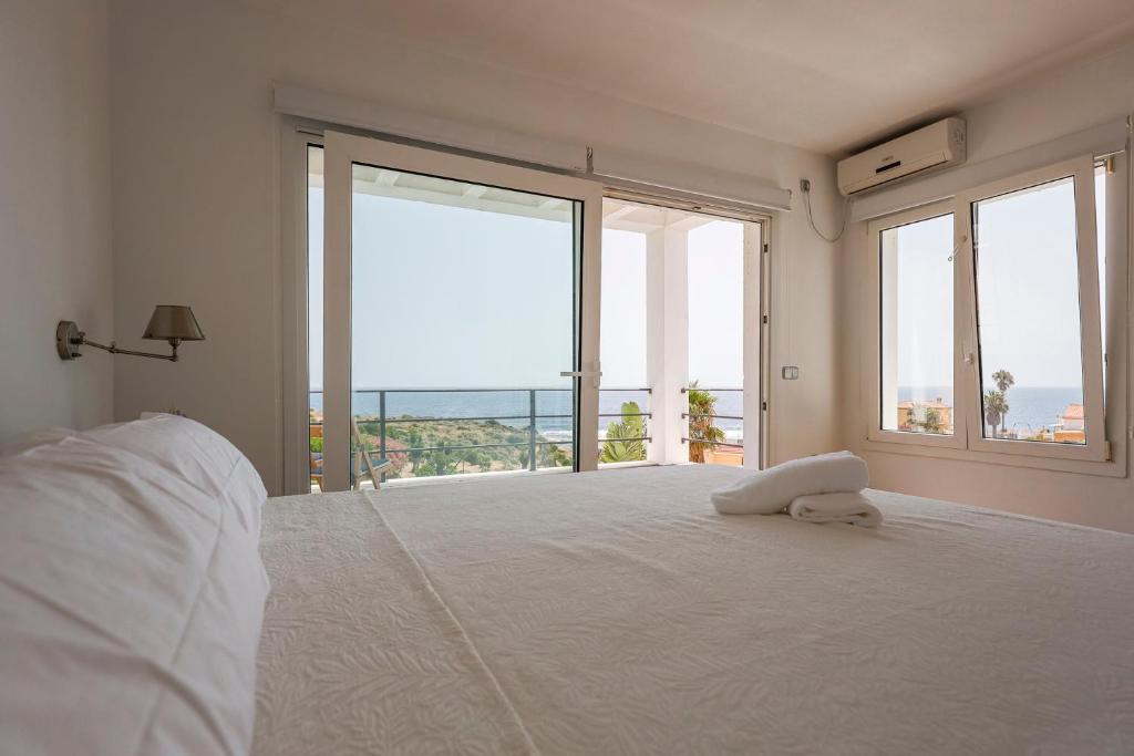 a bedroom with a large white bed with large windows at Cádiz punta carnero 1 in Algeciras
