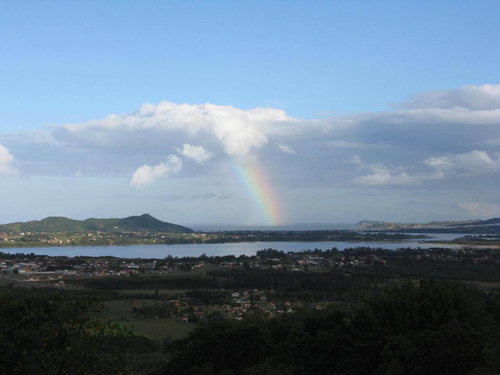 a rainbow in the sky over a river and a city at Portal de Avalon in Praia do Rosa