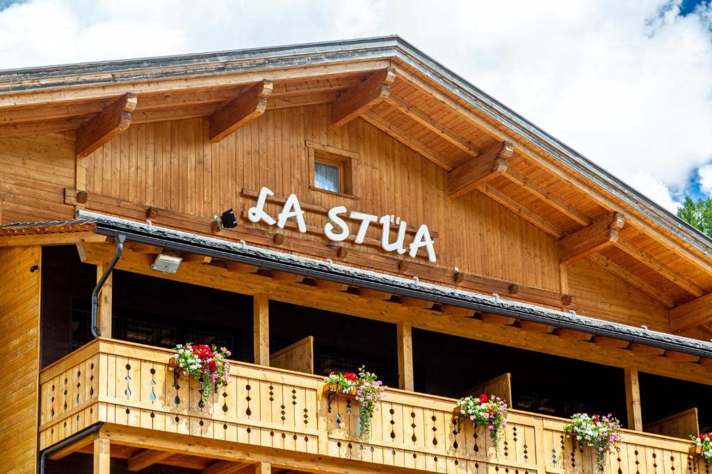 ein Holzgebäude mit einem Schild darauf in der Unterkunft La Stua in St. Kassian