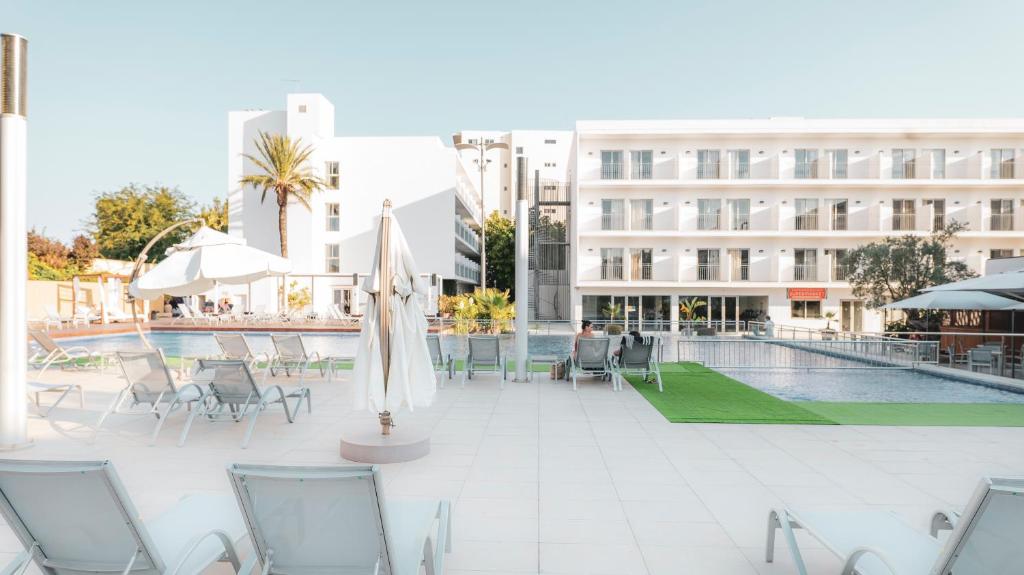 een zwembad met stoelen en parasols naast een gebouw bij Hotel Puchet in San Antonio