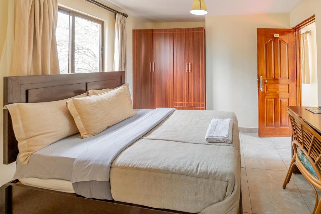 um quarto com uma cama grande e uma cabeceira em madeira em Joy Palace Hotel em Nairobi