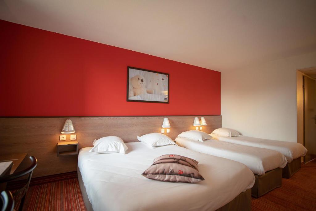 três camas num quarto com uma parede vermelha em Ace Hotel Troyes em Saint-André-les-Vergers