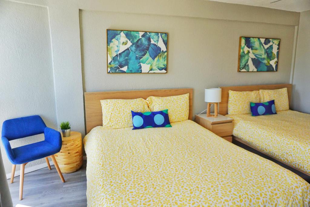 sypialnia z 2 łóżkami i niebieskim krzesłem w obiekcie Daytona Inn Studios w mieście Daytona Beach