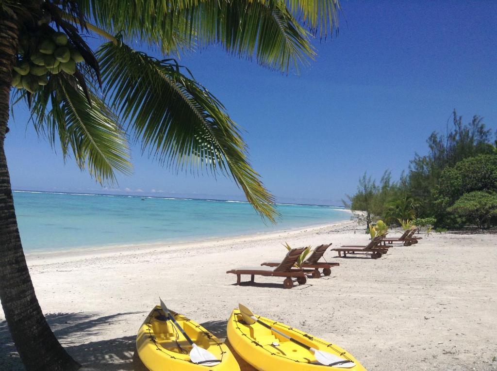 uma praia com bancos e caiaques na praia em Aitutaki Seaside em Arutanga