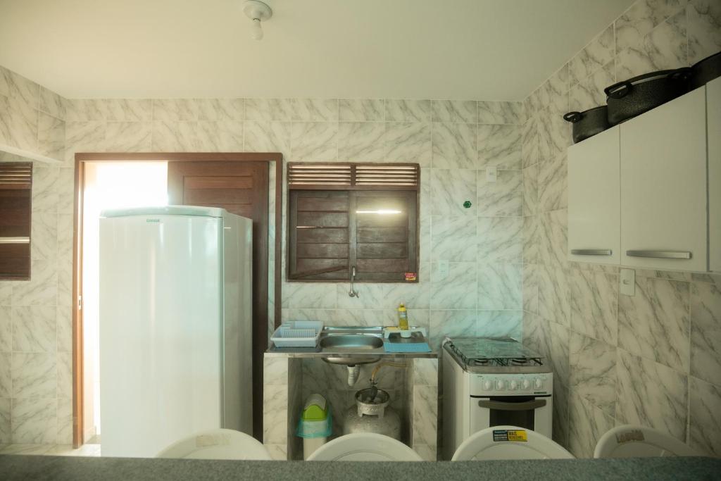 uma pequena cozinha com um lavatório e um frigorífico em Canto do Sabiá Apart Hotel em Barra de Camaratuba