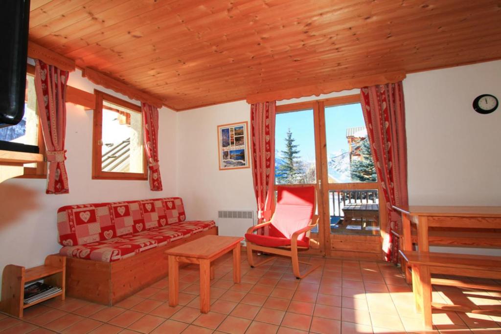 sala de estar con sofá, mesa y ventanas en Le Meï Hameau des Chazals Nevache Hautes Alpes en Névache