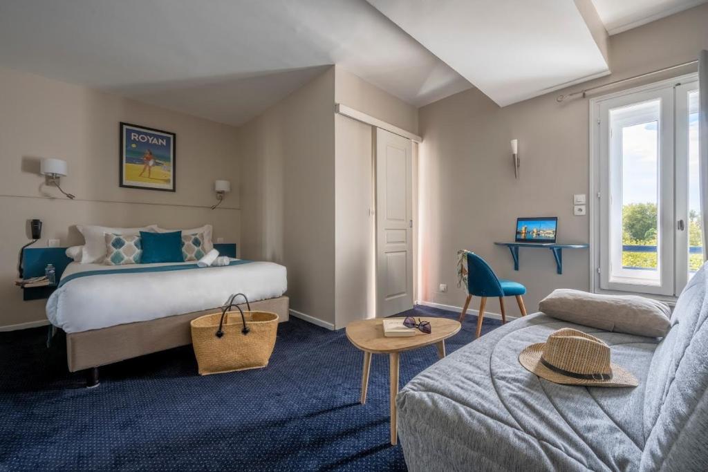 ラ・ロシェルにあるUn Hotel sur le Portのベッドとソファ付きのホテルルーム