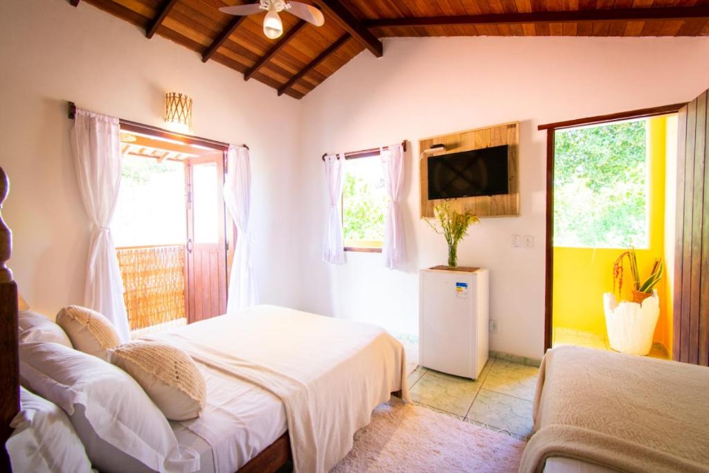 um quarto com 2 camas, uma televisão e janelas em Pousada Por do Sol em Trancoso