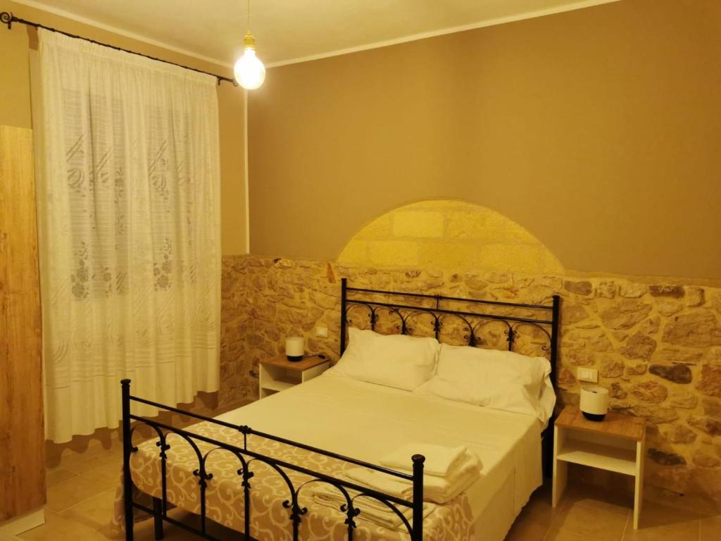 a bedroom with a bed with a stone wall at Cuore di Conchiglia in Custonaci