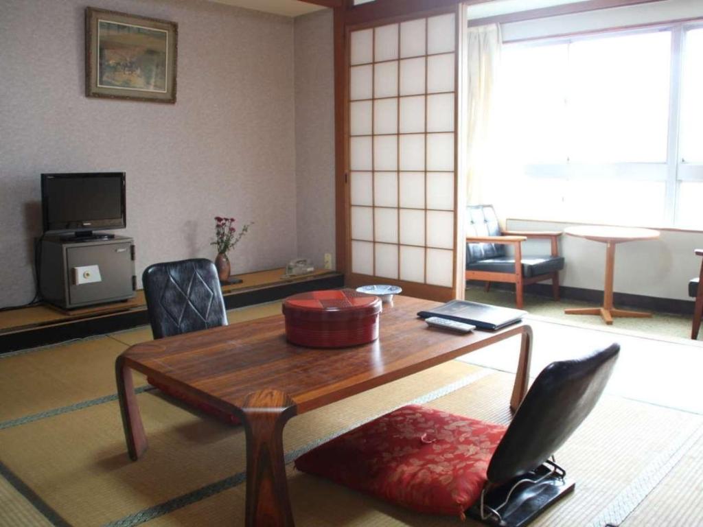 ein Wohnzimmer mit einem Holztisch und Stühlen in der Unterkunft Kochi - Hotel - Vacation STAY 92256 in Kōchi