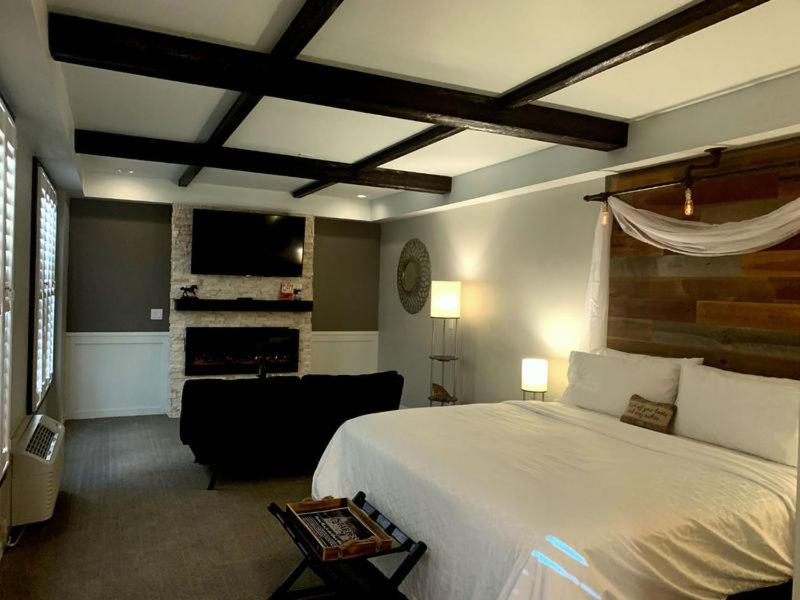 1 dormitorio con cama blanca y chimenea en Cedar Stables Inn & Suites, en Sandusky