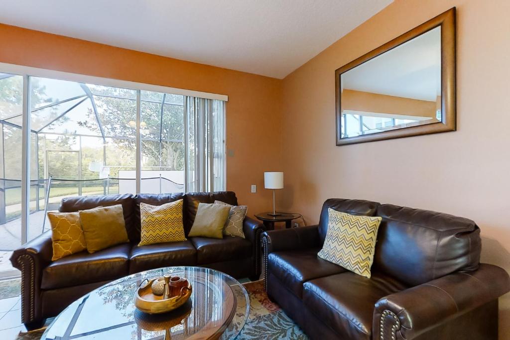 a living room with leather furniture and a mirror at Paradise Palms in Kissimmee