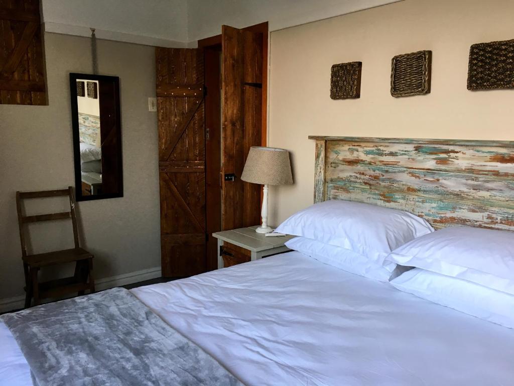 a bedroom with two white beds and a wooden headboard at Kingfisher Cottage in Umkomaas