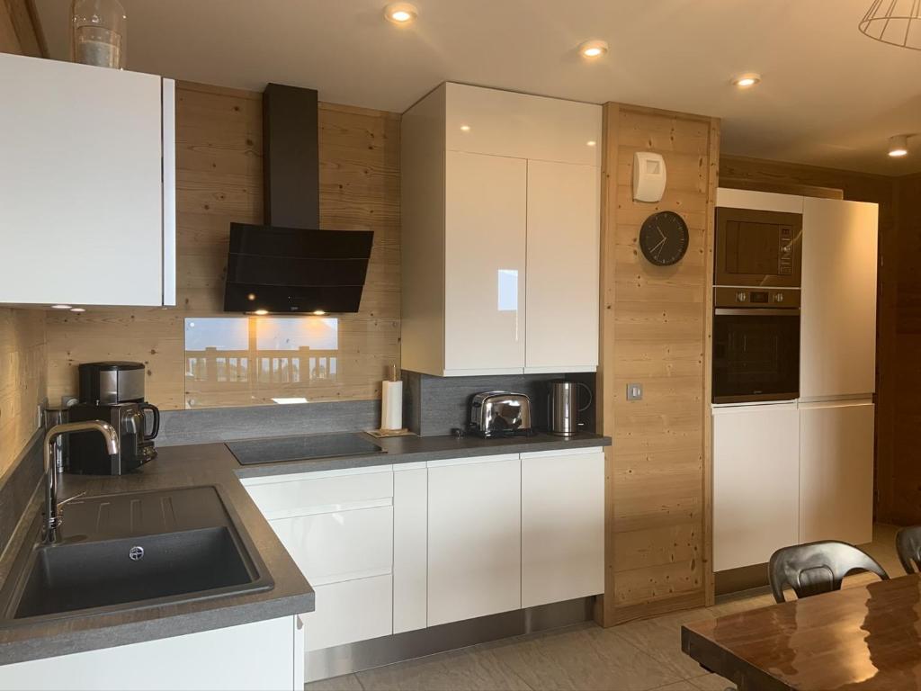 a kitchen with white cabinets and a sink at ODYSSEE D103 Appartement chaleureux sur les pistes in La Toussuire
